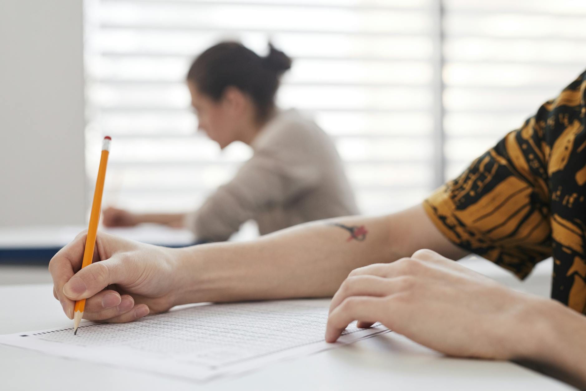 Dłoń studenta zapisująca kartę egzaminacyjną z języka polskiego
