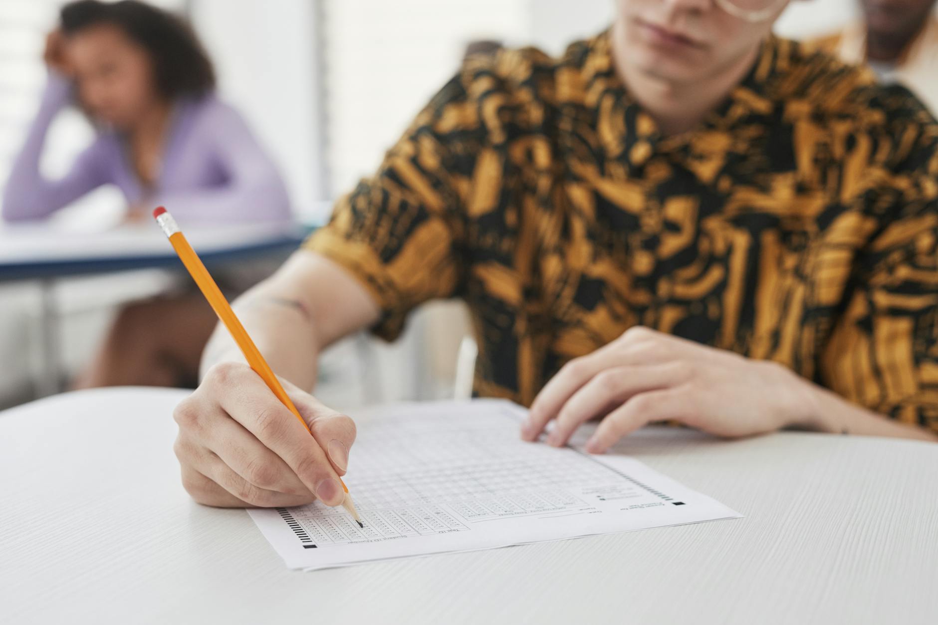 Uczeń pisze odpowiedzi na arkuszu egzaminu w szkolnej sali